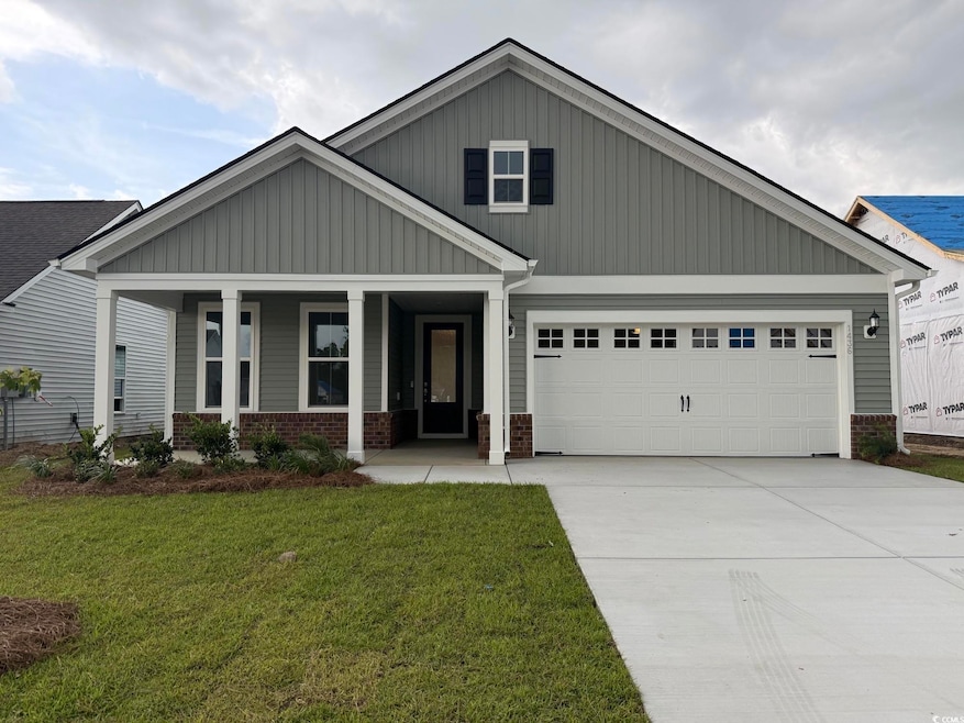 Craftsman house featuring a front yard, concrete driveway, an attached garage, brick siding, and a porch