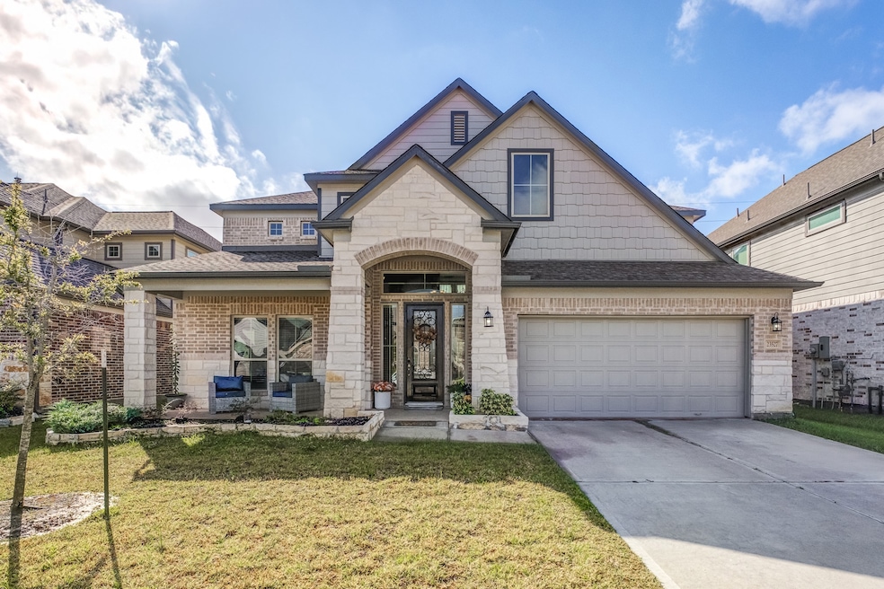 This is a modern, two-story home with a combination of brick and stone exterior. It features a welcoming front porch, a two-car garage, and a neatly maintained lawn. Ideal for a family seeking a stylish and comfortable residence.