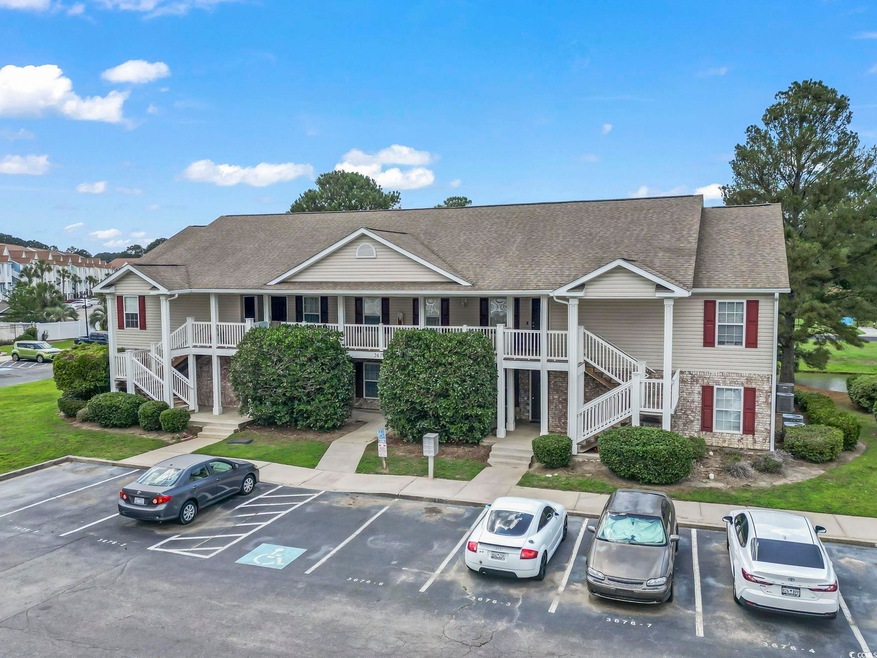 View of property featuring stairway and uncovered parking