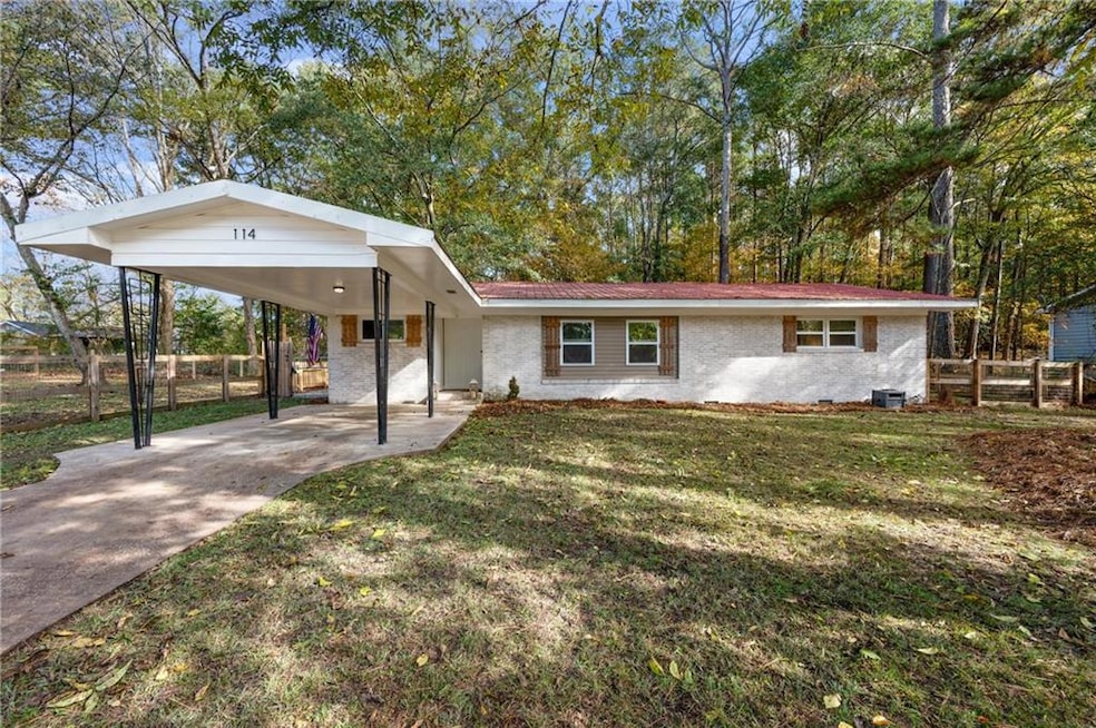 View of front facade with brick siding, driveway, a carport, and view of scattered trees