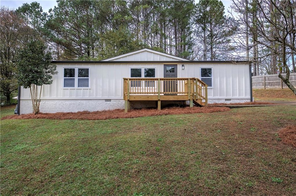 Rear view of house featuring a deck and a yard