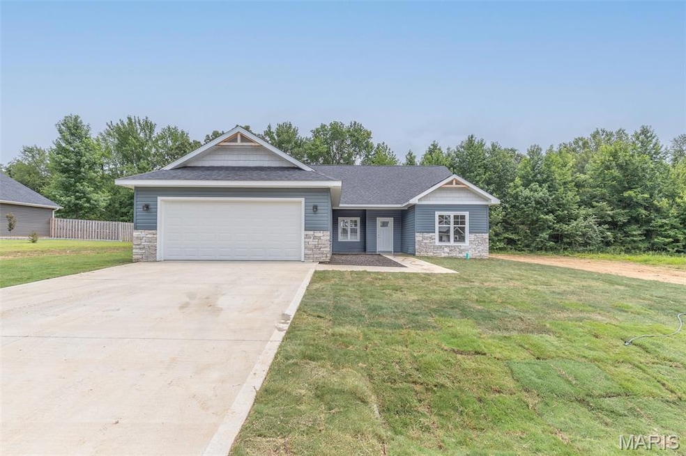 View of front facade with stone siding, a shingled roof, driveway, and an attached garage