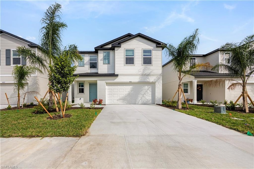 Traditional-style home featuring a front yard, concrete driveway, a garage, and stucco siding
