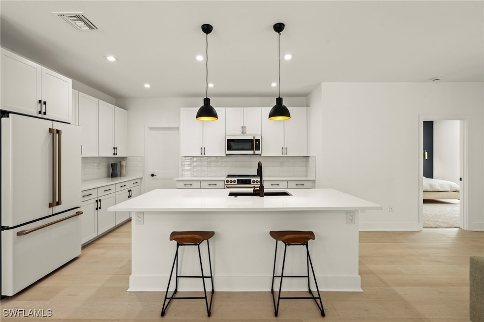 Kitchen featuring an island with sink, sink, white