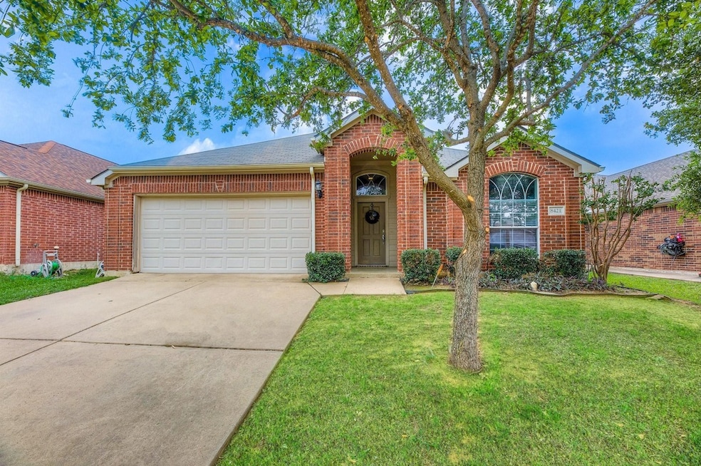 View of front of house with a front yard, concrete driveway, brick siding, a garage, and roof with shingles