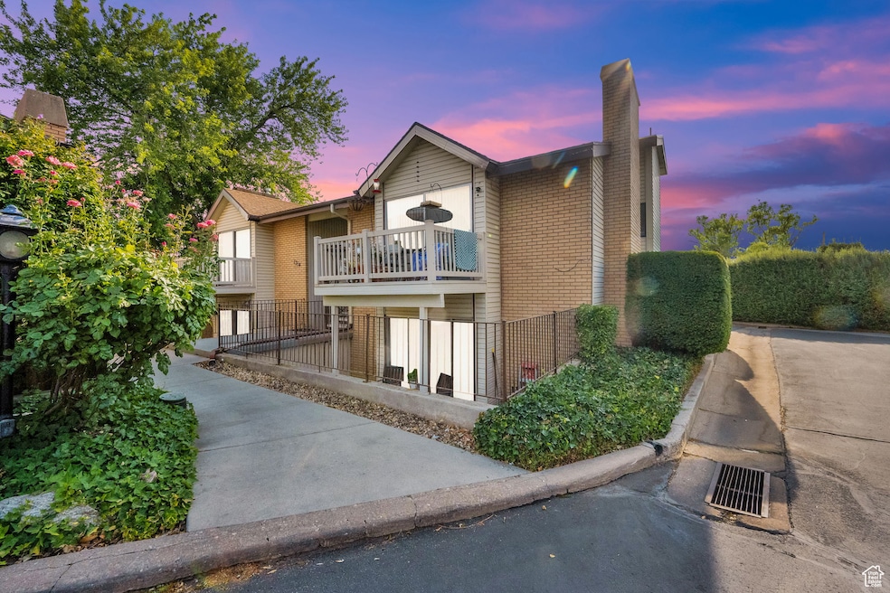 View of front of house with a chimney, brick siding, and a balcony