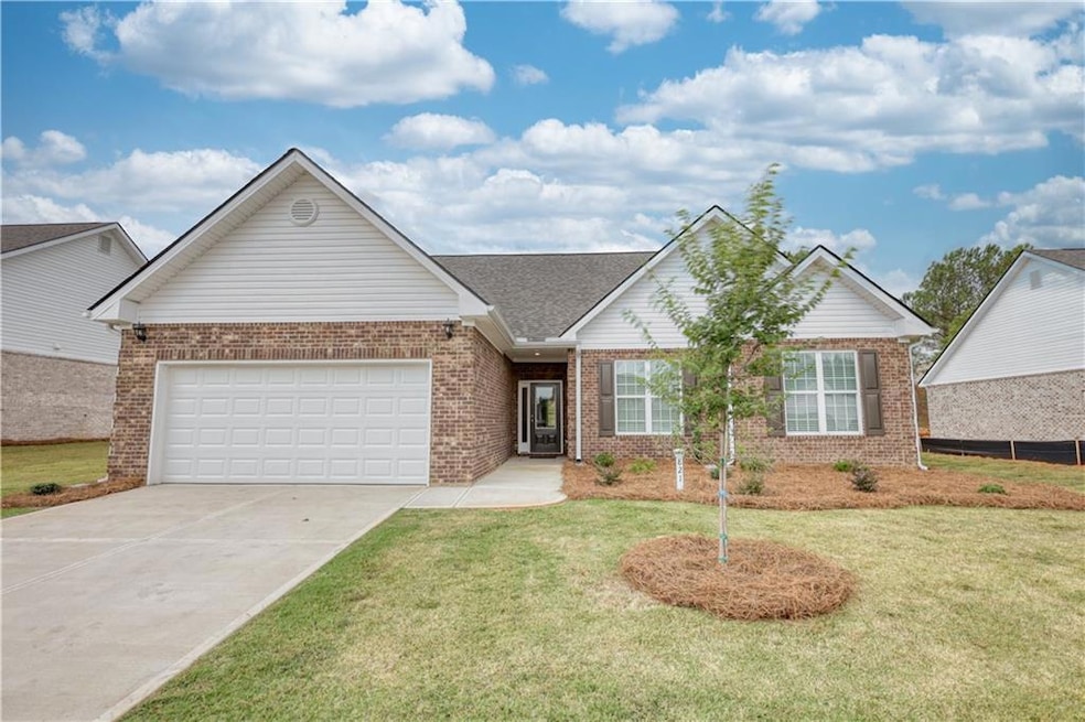 Ranch-style house featuring concrete driveway, bri