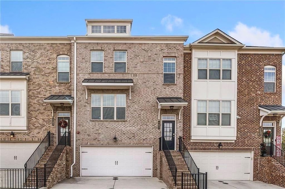 Multi unit property featuring brick siding, an attached garage, and driveway