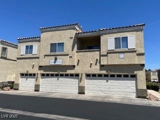 Back of property with a garage, driveway, and stuc