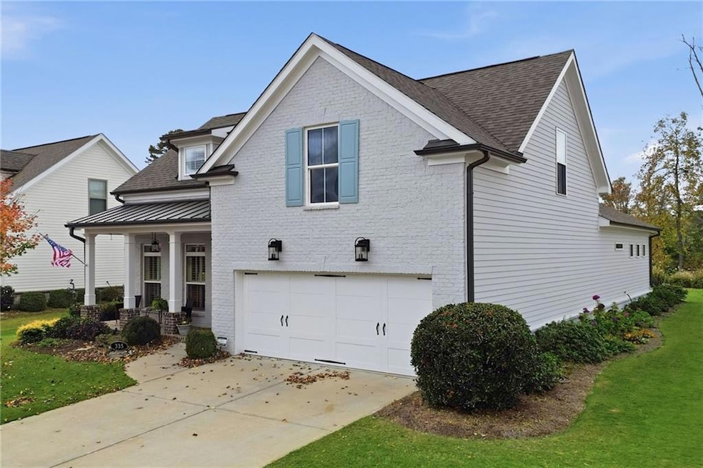 Traditional-style house with a shingled roof, a porch, a garage, brick siding, and a front lawn