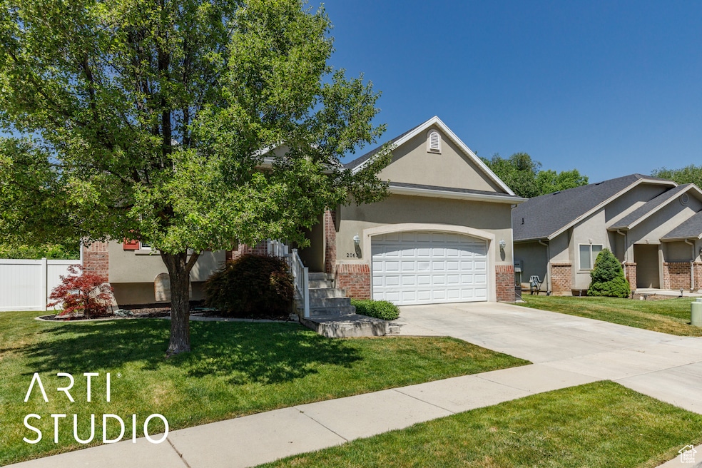 View of front of house with brick siding, driveway, a garage, and stucco siding