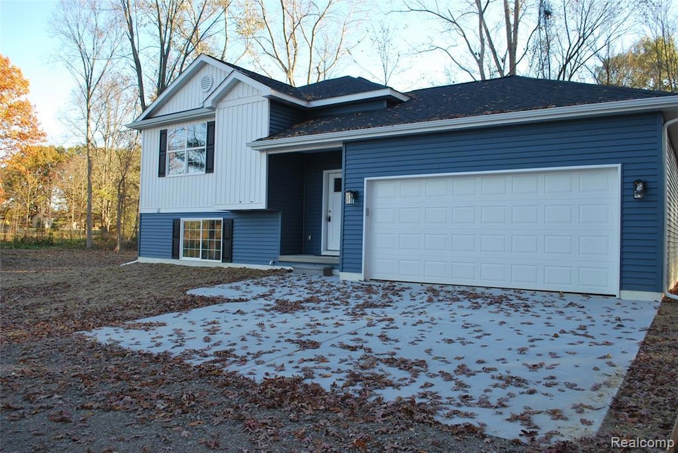 Split level home featuring a garage, roof with shingles, and driveway