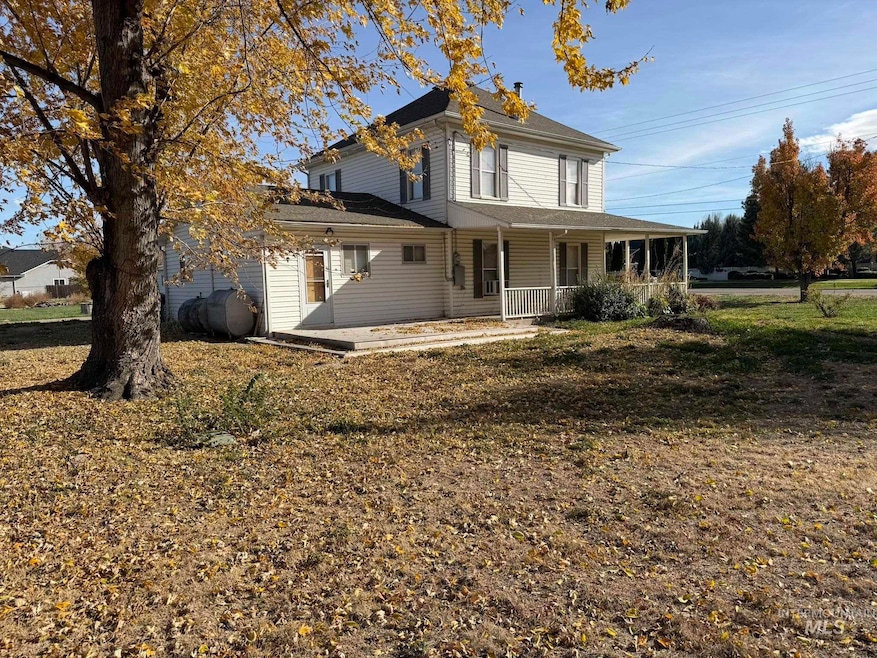 View of front of property with oil tank, a porch, a front lawn, and a shingled roof