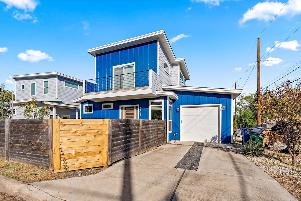 Modern home featuring concrete driveway, a fenced front yard, a balcony, a garage, and a gate