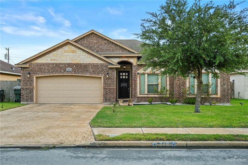French country home featuring brick siding, driveway, a front yard, and an attached garage