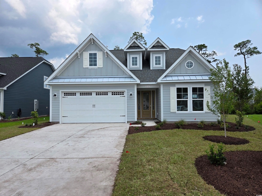 View of front of property featuring board and batten siding, driveway, a front lawn, and roof with shingles