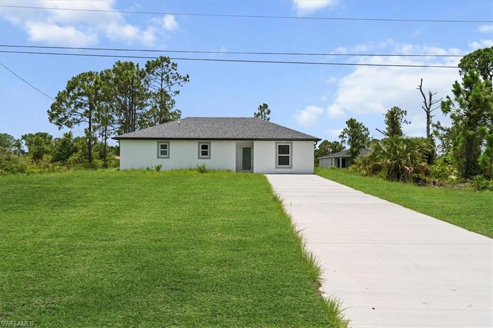 Single story home featuring concrete driveway, stucco siding, and a front yard