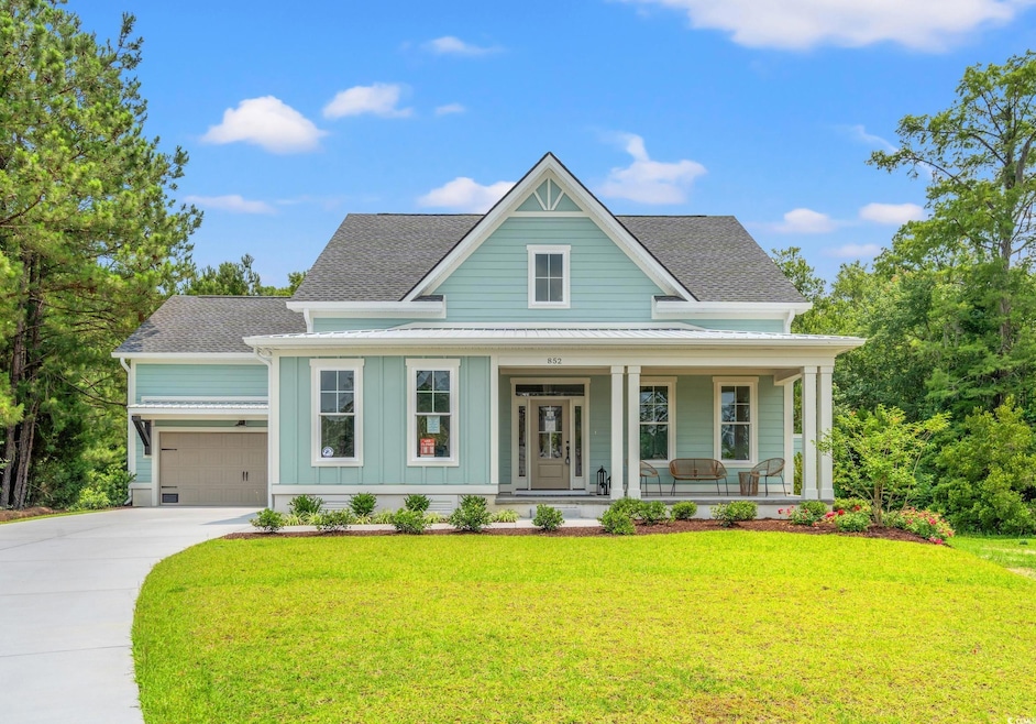 View of front of house featuring covered porch, a shingled roof, board and batten siding, a front yard, and driveway