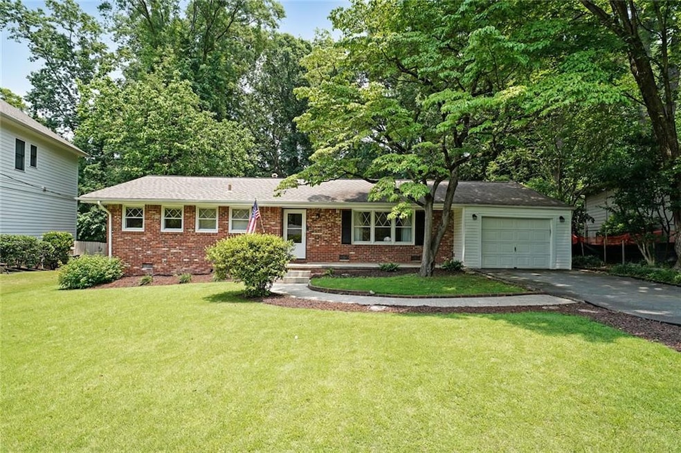 Ranch-style home with driveway, brick siding, crawl space, a front yard, and an attached garage