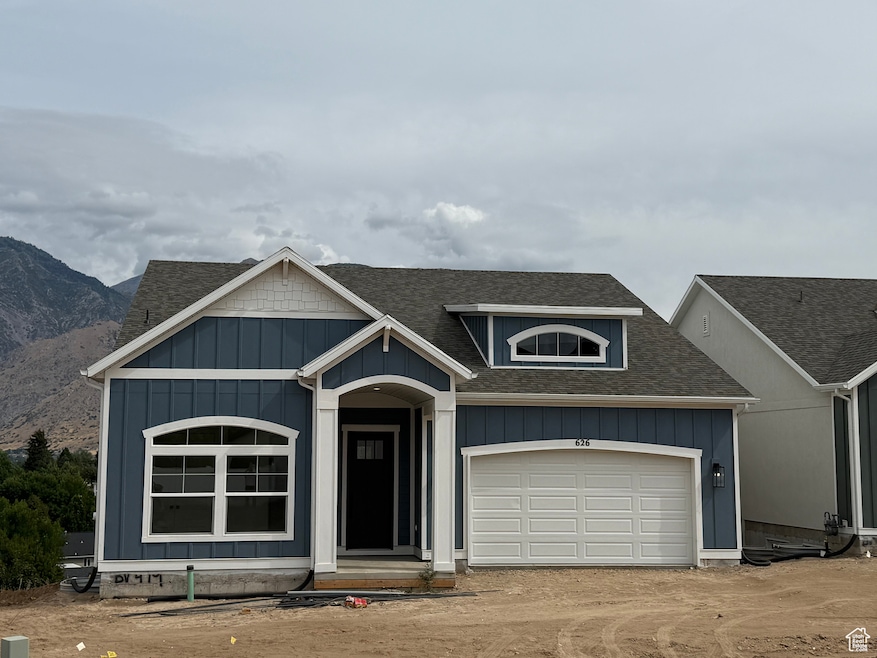 View of front facade featuring roof with shingles, board and batten siding, and driveway