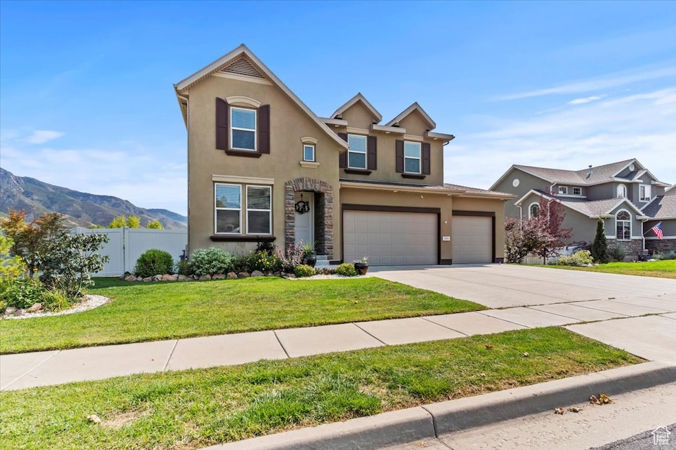 Traditional home with stucco siding, concrete driveway, a mountain view, and an attached garage