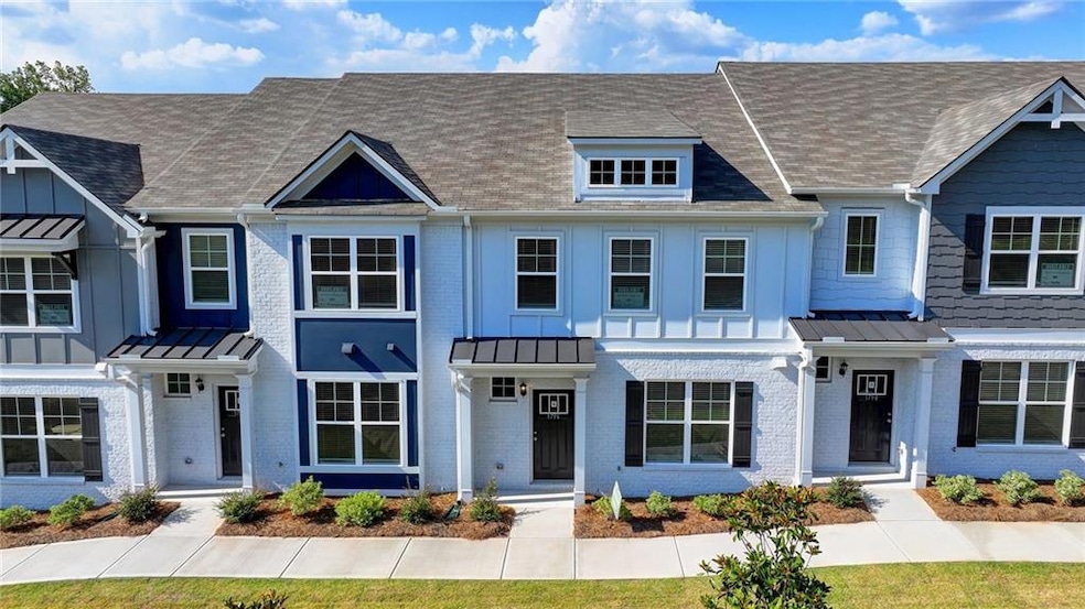 Multi unit property featuring brick siding, roof with shingles, and a standing seam roof