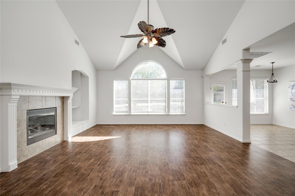 Unfurnished living room featuring plenty of natural light, dark wood-style floors, a fireplace, high vaulted ceiling, and ceiling fan