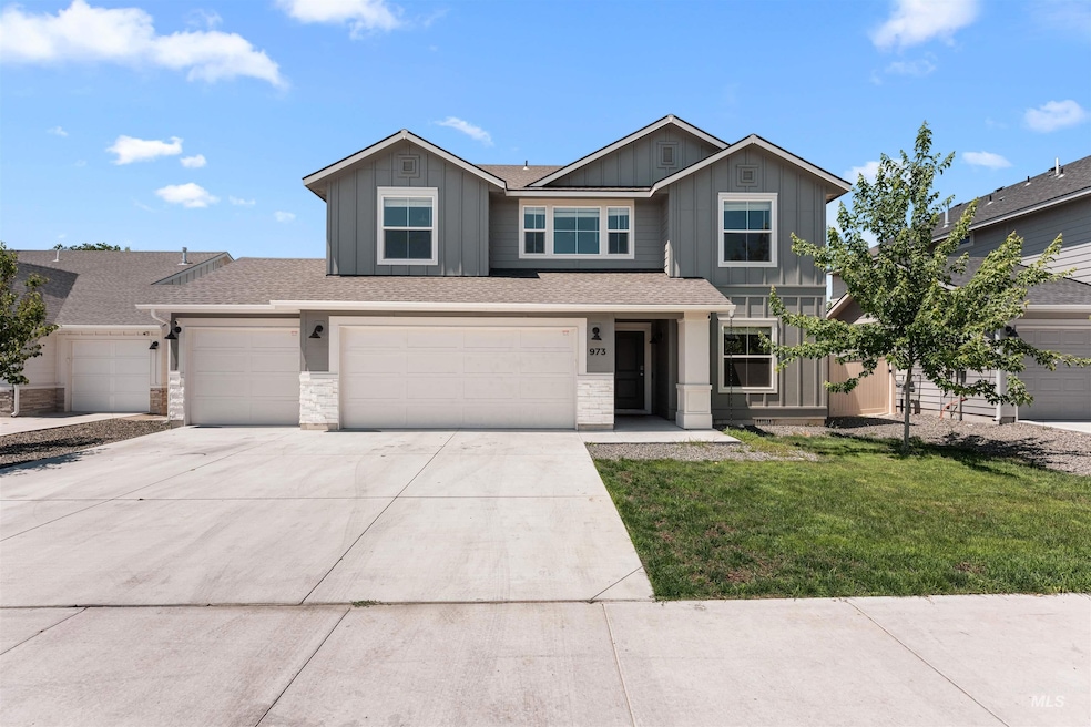View of front of property featuring board and batten siding, driveway, a front yard, and stone siding