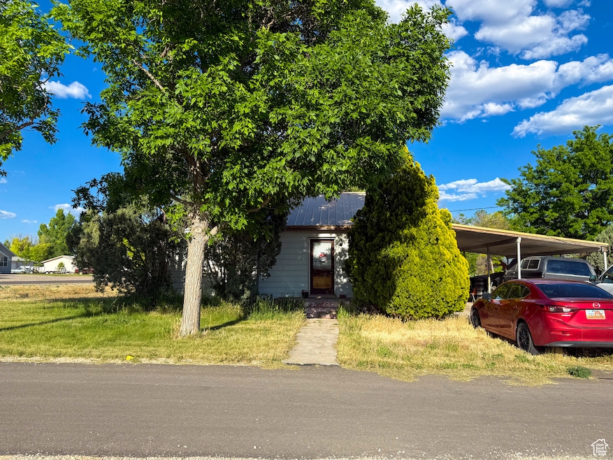 View of property hidden behind natural elements featuring an attached carport