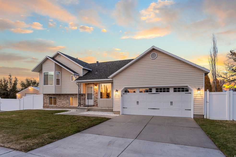 Tri-level home with driveway, brick siding, and a gate