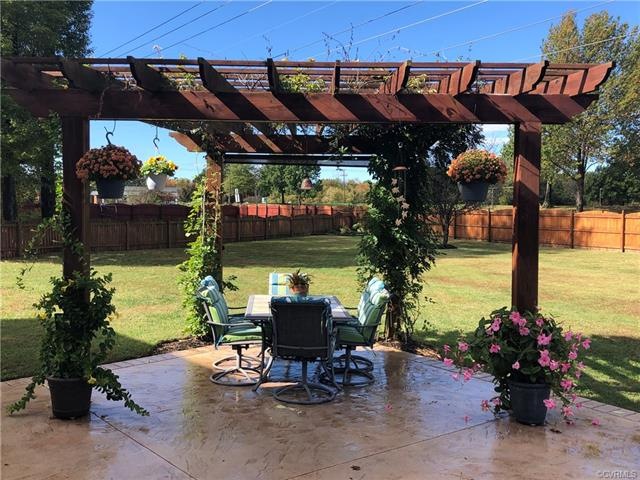 Pergola, patio and huge yard in bloom in summertime.