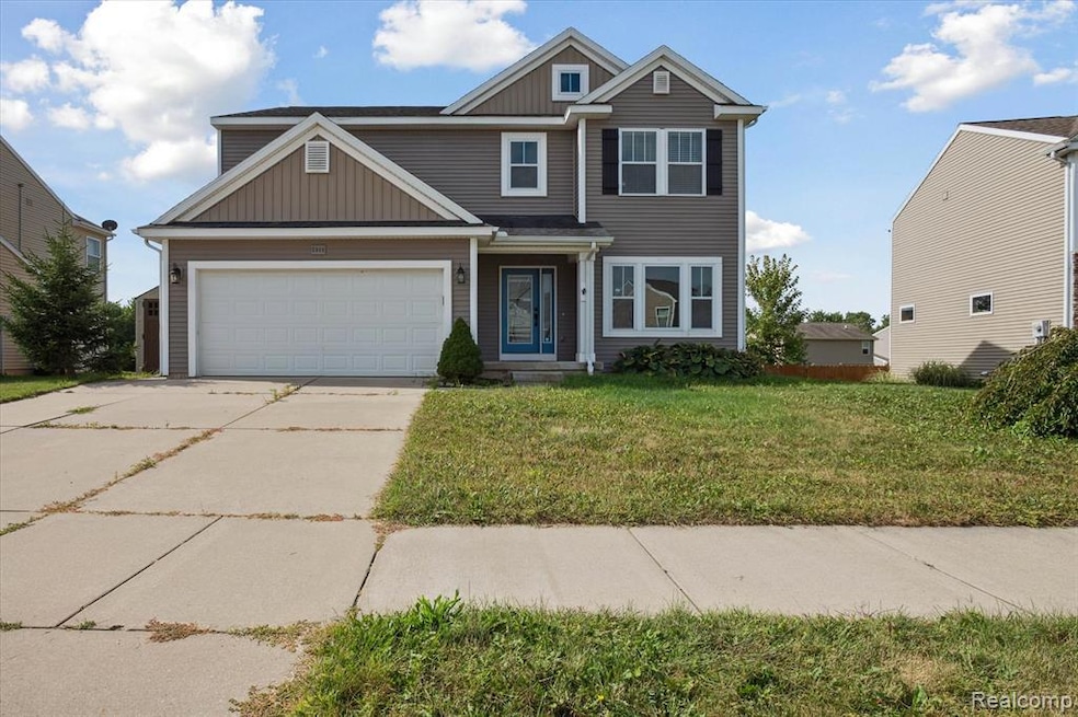 View of front facade featuring board and batten siding, a front yard, and concrete driveway