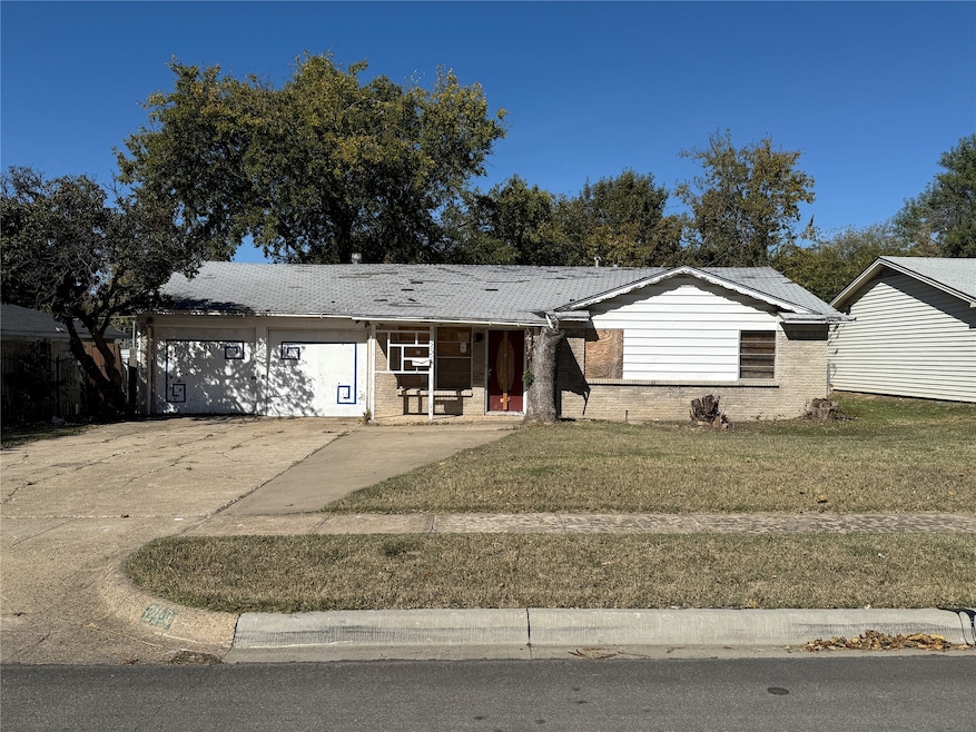 Ranch-style home with brick siding, covered porch, concrete driveway, and a front lawn