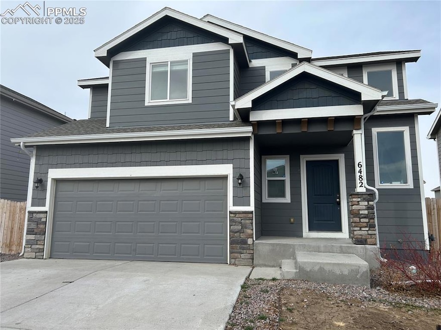 Craftsman-style house with stone siding, driveway, and an attached garage