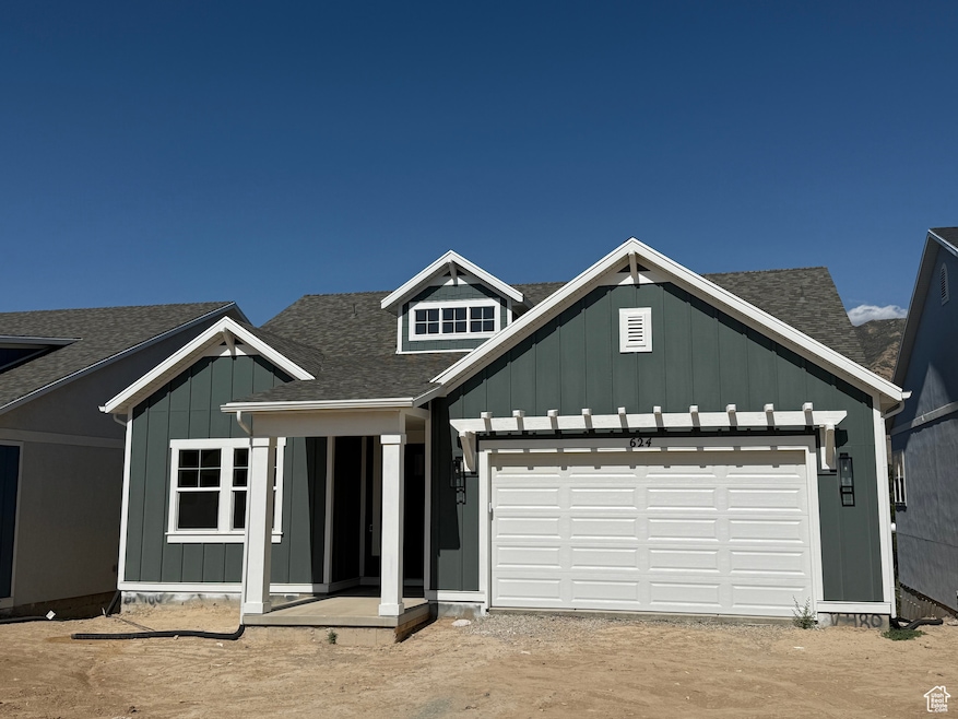 View of front of house featuring board and batten siding, roof with shingles, a garage, dirt driveway, and covered porch