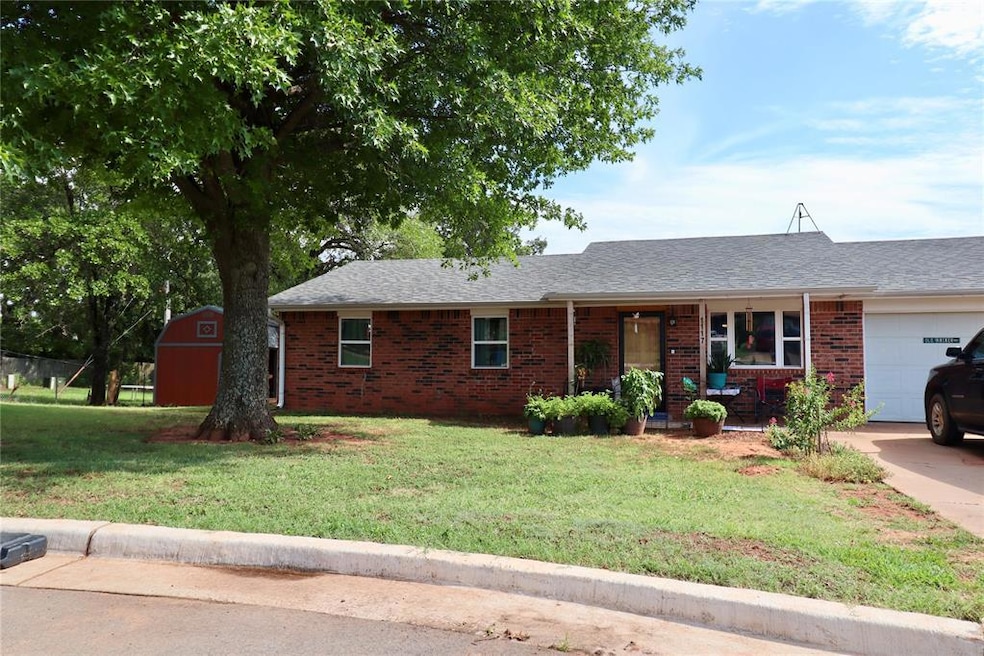 Ranch-style home with a garage, a front yard, a porch, roof with shingles, and brick siding