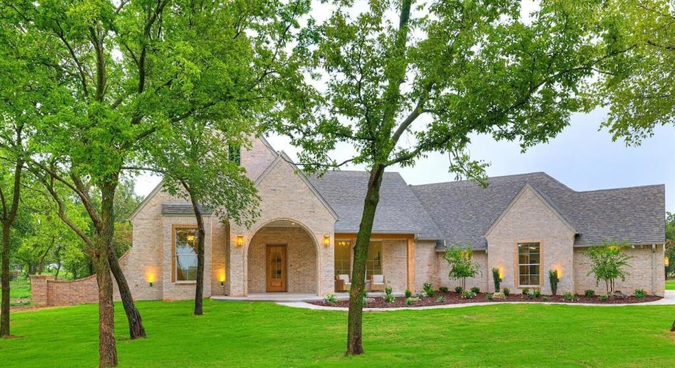 View of front facade with a front yard, brick siding, covered porch, and a shingled roof