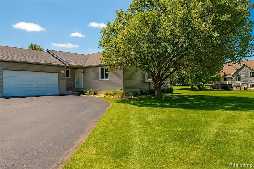 Ranch-style house featuring a garage, driveway, a front yard, and a shingled roof