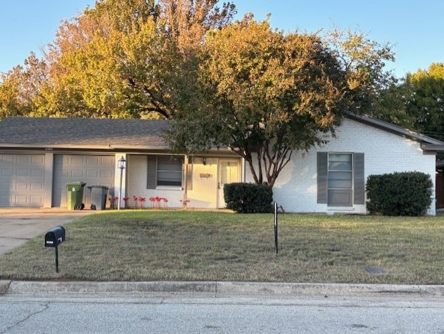 Ranch-style house featuring a front yard, brick siding, and an attached garage