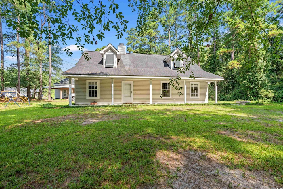 New england style home with a front lawn, a chimney, a porch, and a shingled roof