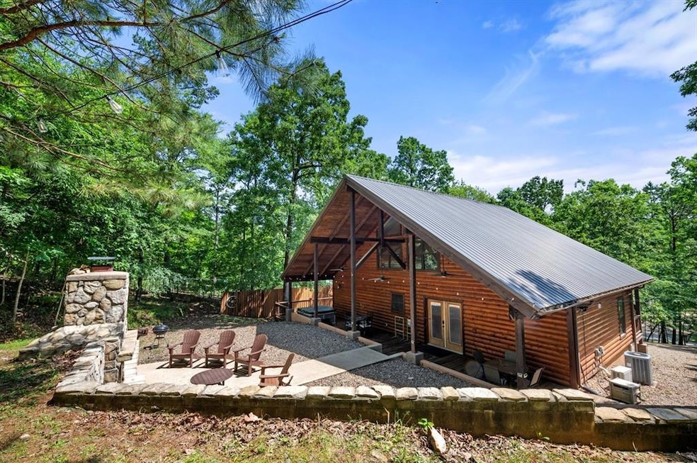 Rear view of house with log veneer siding, a patio, french doors, metal roof, and central AC unit