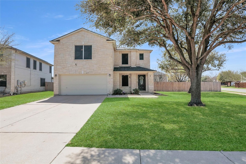 Traditional home featuring fence, an attached garage, concrete driveway, a front lawn, and stone siding