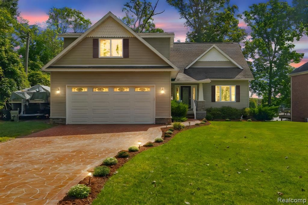 View of front of house featuring a front lawn, driveway, a garage, and a shingled roof