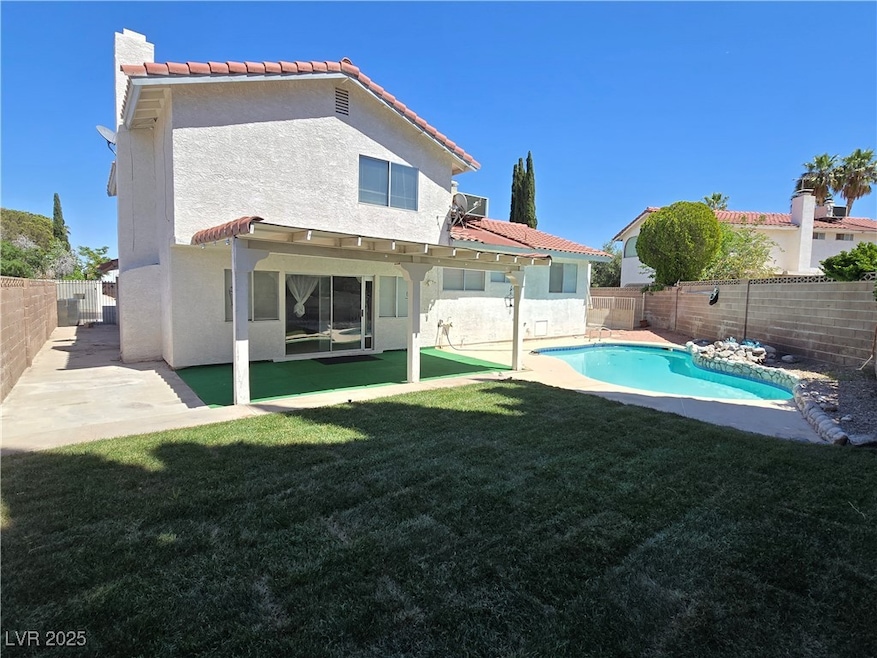Rear view of house featuring a yard, a tile roof,