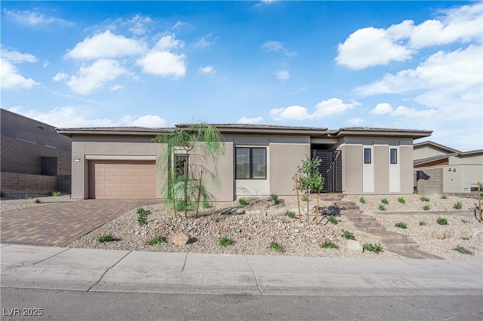 Prairie-style house featuring stucco siding, decorative driveway, and an attached garage