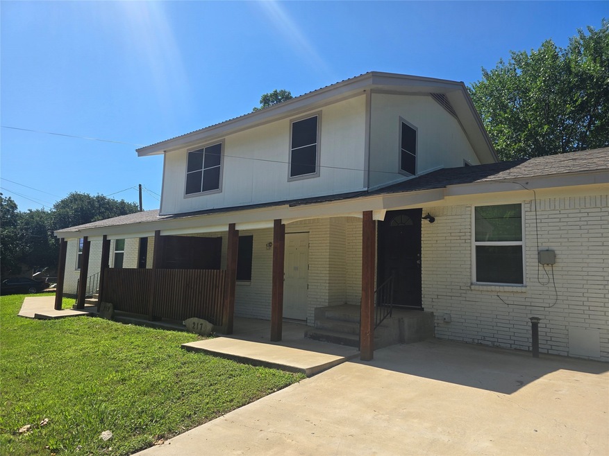 Back of house with brick siding, covered porch, a yard, and a shingled roof