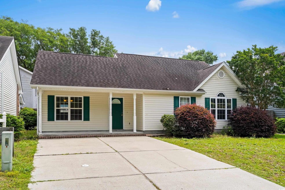 View of front of home with a porch, roof with shingles, a front yard, and driveway