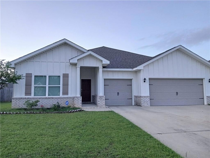 View of front of property featuring a garage, a front yard, concrete driveway, a shingled roof, and board and batten siding