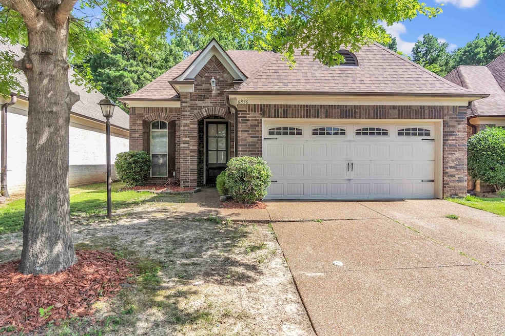 French country inspired facade featuring a shingled roof, brick siding, a garage, and concrete driveway
