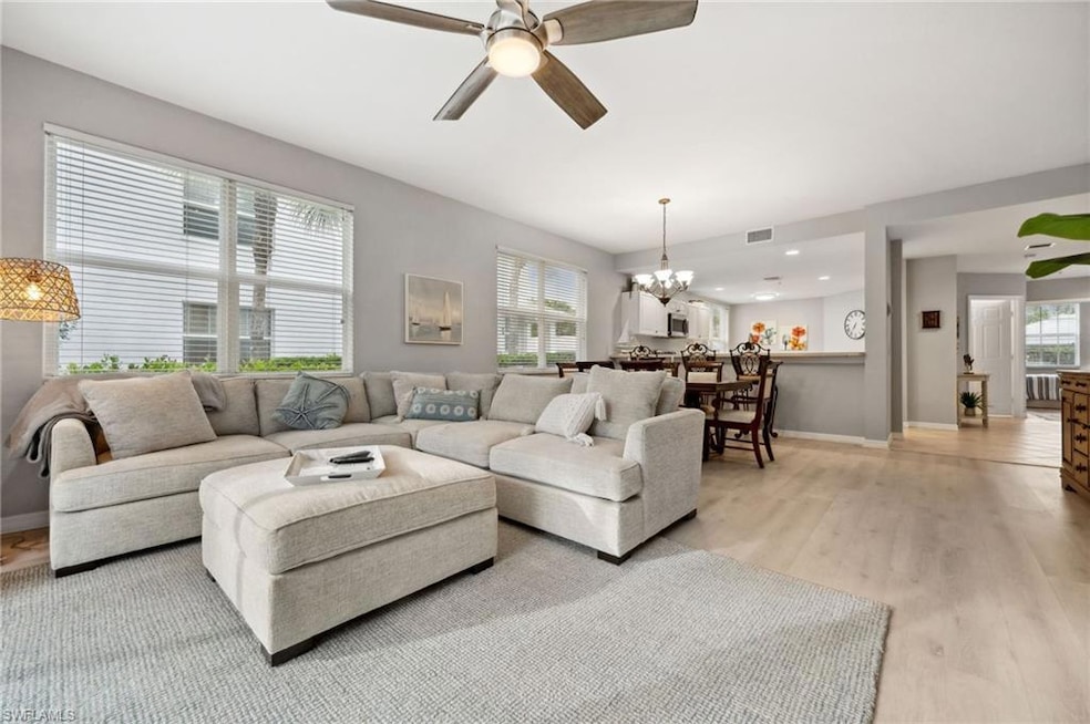 Living room with light hardwood / wood-style flooring and ceiling fan with notable chandelier
